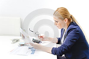 Business woman analyzing investment charts with calculator and laptop