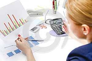 Business woman analyzing investment charts with calculator and laptop