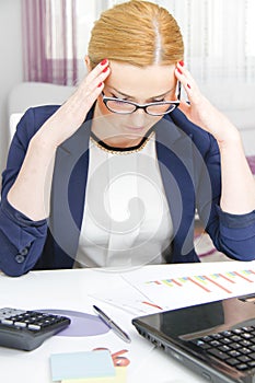 Business woman analyzing investment charts with calculator and laptop