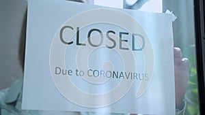 Business woman attaching business closed sign at shop entrance due to financial crisis from coronavirus covid-19