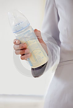 Business, woman and baby bottle with mom in suit, working and balance a career with motherhood. Hand, closeup and mother