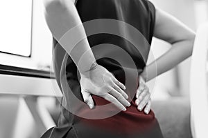 Business woman with back pain an office. Healthcare and medical concept - Black and White color image