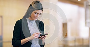 Business woman browsing on a phone, scrolling through social media or typing a text message online while standing in an