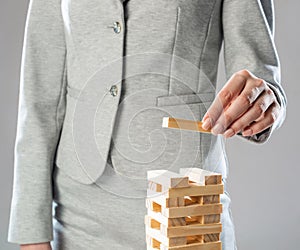 Business woman building tower from wooden blocks