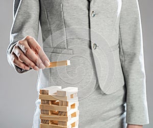 Business woman building tower from wooden blocks