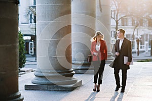 Business Woman and Business Man Use Smartphone and Talk on the Busy Big City Street. Both Look Exquisitely Stylish