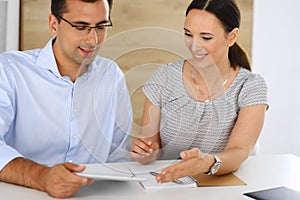 Business woman and businessman discussing questions while using a computer in modern office. Group of diverse people