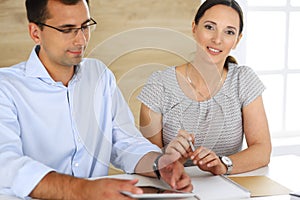 Business woman and businessman discussing questions while using a computer in modern office. Group of diverse people