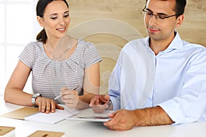 Business woman and businessman discussing questions while using a computer in modern office. Group of diverse people