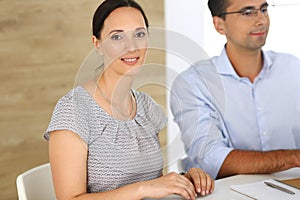 Business woman and businessman discussing questions while using a computer in modern office. Group of diverse people