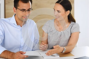 Business woman and businessman discussing questions while using a computer in modern office. Group of diverse people