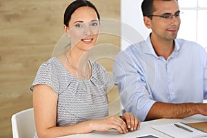 Business woman and businessman discussing questions while using a computer in modern office. Group of diverse people