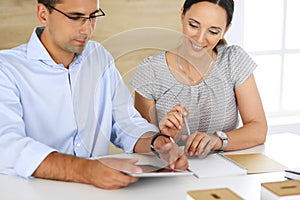 Business woman and businessman discussing questions while using a computer in modern office. Group of diverse people