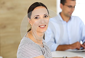 Business woman and businessman discussing questions while using a computer in modern office. Headshot of female hispanic