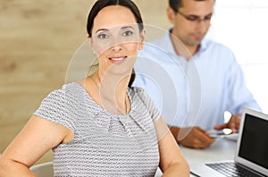 Business woman and businessman discussing questions while using a computer in modern office. Headshot of female hispanic