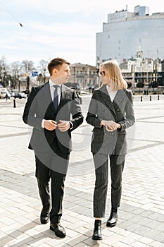 A business woman and a businessman are walking around the city outside the office, planning and discussing a new project