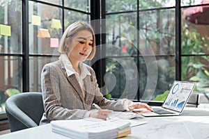 Business woman calculating monthly expenses, managing budget. Woman sitting at table using calculator to calculate tax