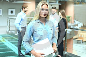 Business woman in casual wear with her staff, people group in background at modern bright office.