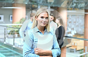 Business woman in casual wear with her staff, people group in background at modern bright office.