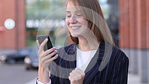 Business Woman Celebrating Success while Using Smartphone