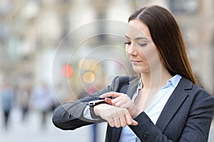 Business woman checking smart watch on city street