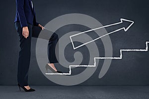 Business woman climbing stairs against blue background with white arrow