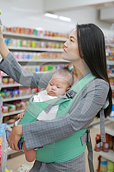 Business woman in Convenience Store while carrying her baby boy by hipseat