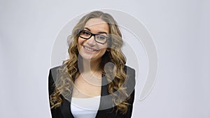 Business woman coquettishly smiling while looking at camera on gray background