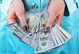 Business woman counting money in hands. Handful of money. Offering money. Women`s hands hold money denominations of 100 dollars.