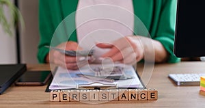 Business woman counts dollars text on cubes persistence