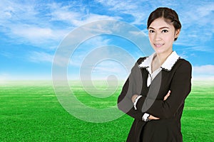 Business woman , crossed arms, with green grass field and blue s