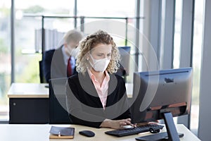 Business woman with curly blonde hair wearing a mask sitting in office, Concept,contagious disease, coronavirus, covid2019 photo