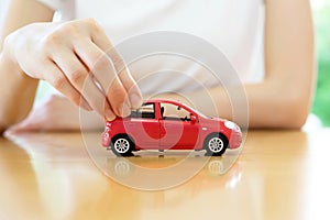 A Business woman by a desk holding a toy car.