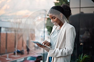 Business woman on a digital tablet outside a modern office alone. Smiling corporate worker looking at web and social