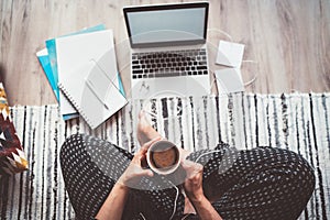 Business woman dressed pajamas enjoying morning coffee with heart shape foam sitting on living room floor office with laptop,