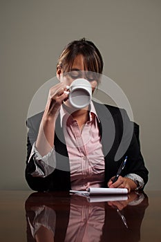 Business woman drinking coffee during meeting