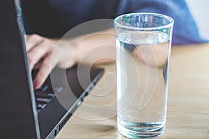 Mujer de negocios bebiendo fresco Agua mientras en negocios sobre el computadora notas 