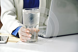 Business woman drinking fresh water while working at the office, A glass of drinking water on office desk