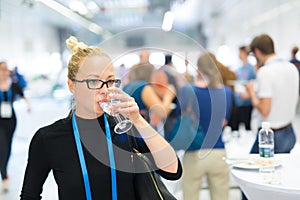 Business woman drinking glass of water during break at business conference.