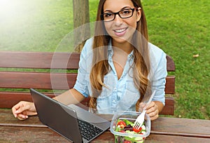 Business woman eating salad on lunch break in city park living healthy lifestyle. Happy smiling young businesswoman take lunch