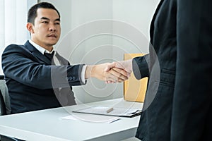 Business woman employee in suit shaking hands with boss after signing on resignation letter and carrying packed