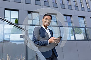 Business woman enjoys cellphone fun and smiling, African American boss businesswoman outside office in business suit