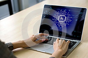 Business woman is entering data on her laptop computer, which prominently exhibits the AI logo, symbolizing her engagement in