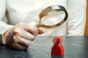 Business woman examines a red man`s figure through a magnifying glass. Analysis of the personal qualities of the employee. photo