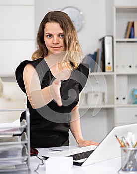Business woman extending her hand for handshake in modern office