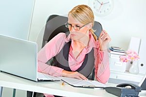 Business woman in eye glasses working on laptop