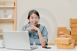 Business woman feeling happy smiling and looking to camera while working in her office at home. Beautiful Asian young entrepreneur