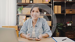 Business woman feeling happy smiling and looking to camera while working in her office at home. Beautiful Asian young entrepreneur