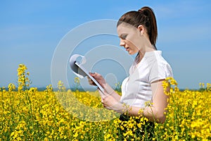 Business woman in flower field outdoor look on clipboard. Young girl in yellow rapeseed field. Beautiful spring landscape, bright