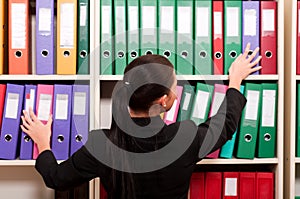 Business woman in front of shelves with folders